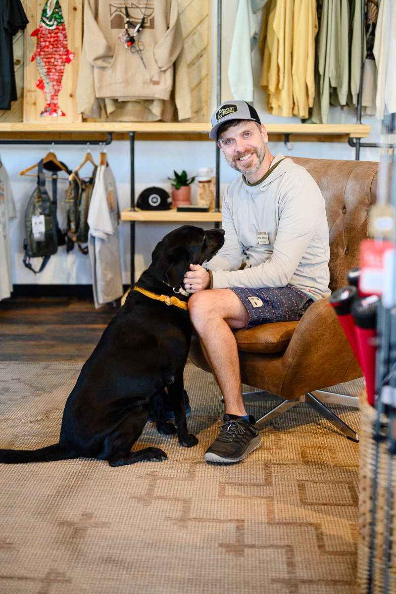 branding photos for small business in denver colorado as the owner of the shop sits with his dog in the foyer