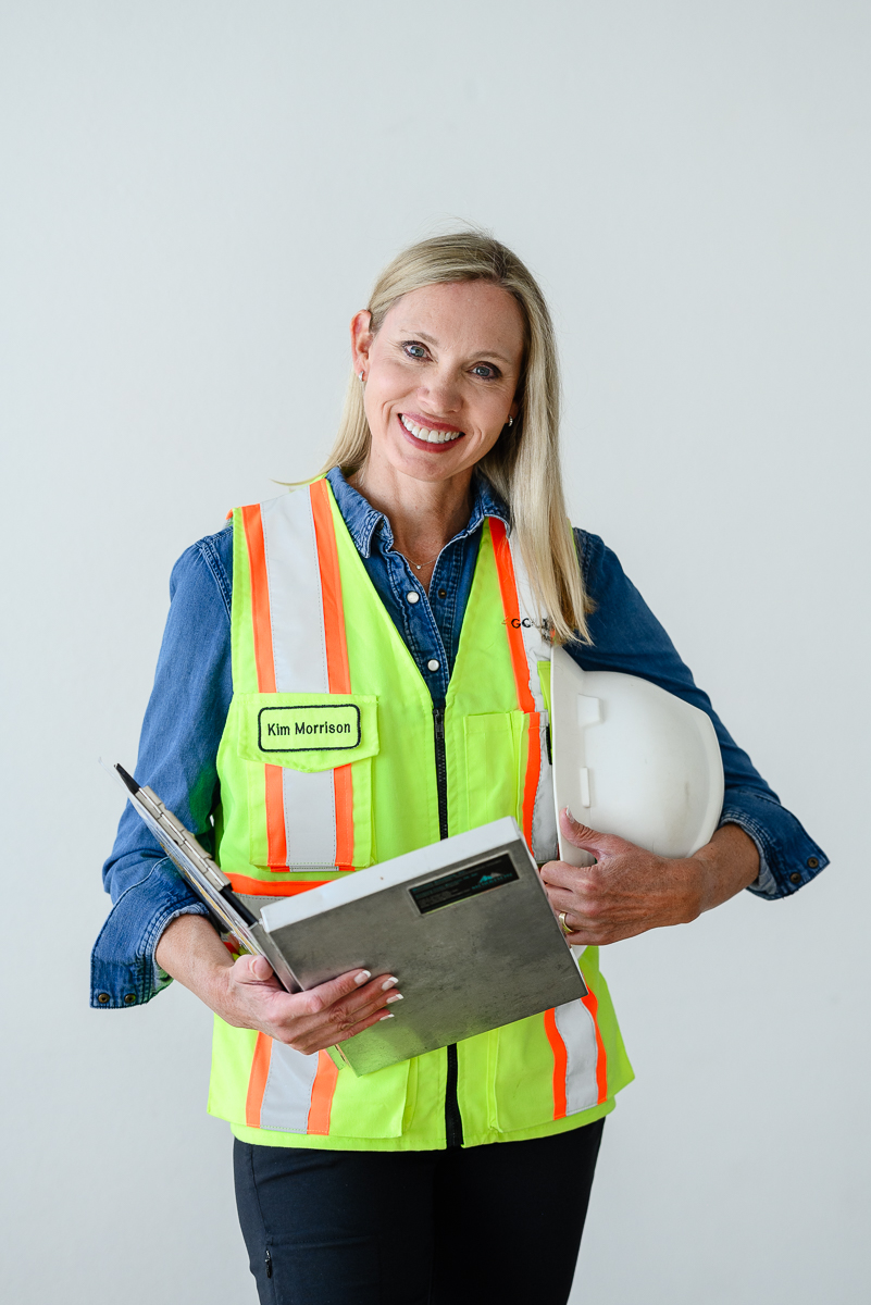 Denver photographers captures business headshot with woman wearing a construction safety vet while holding a clipboard